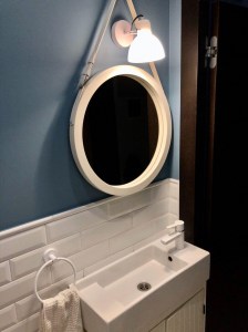 Круглое зеркало в раме белого цвета на кожаном ремне в ванной