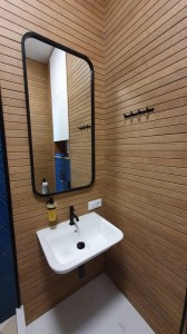 Прямоугольное зеркало в черной раме с закругленными углами в интерьере ванной