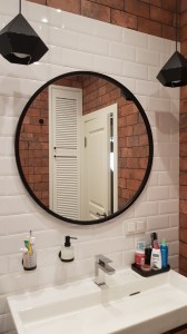 Настенное круглое зеркало в черной раме в ванную